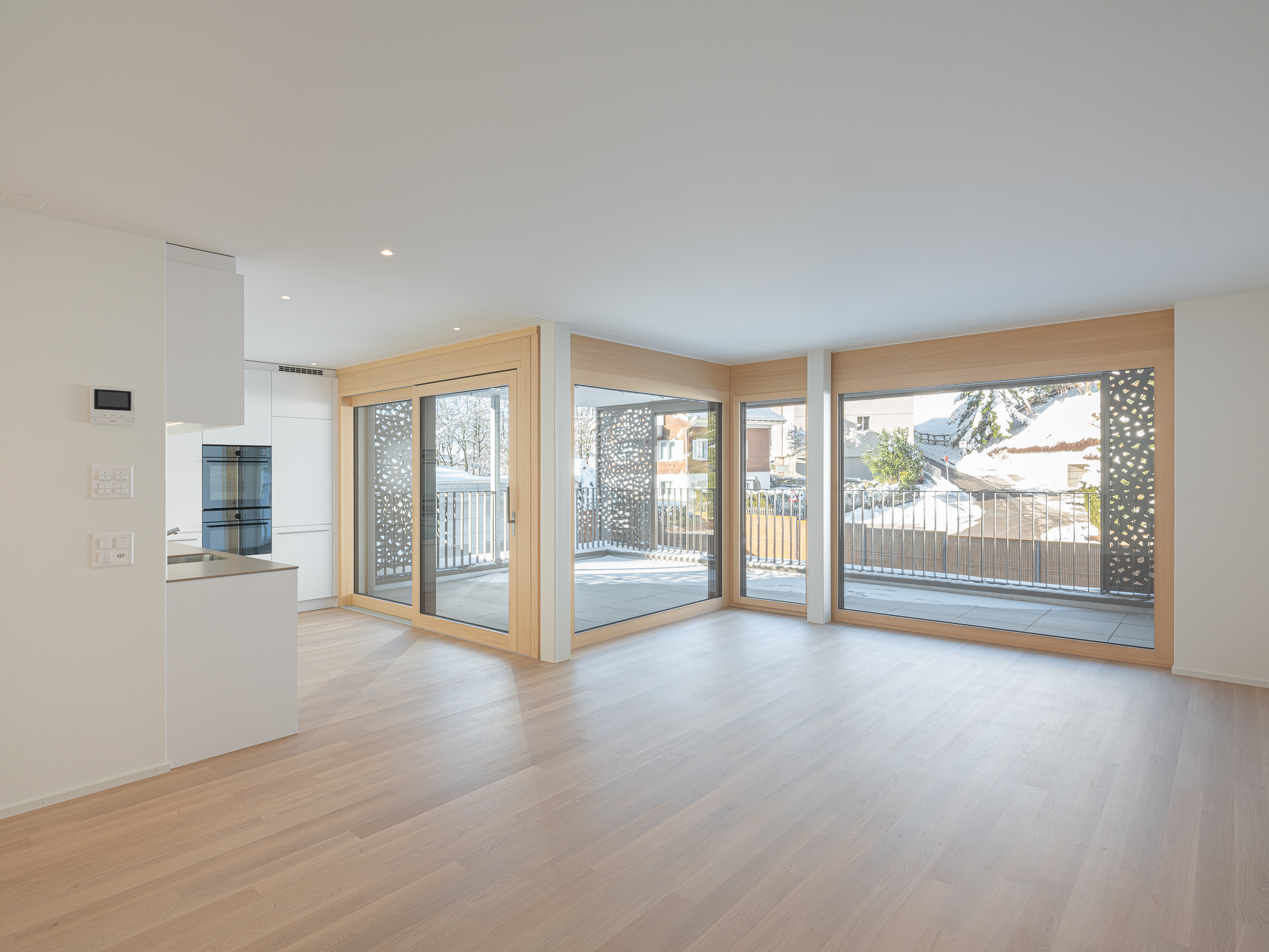 Offener Wohnraum mit Küche, Ess- und Wohnzimmer mit Ausblick auf einen Balkon.
